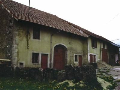 Mesnois, Jura, avr 1998 caue39. Ferme bloc de volume simple, maisons en bande et porte de grange étirée en hauteur. les pierres levées séparent la parcelle - MESNOIS (39130)