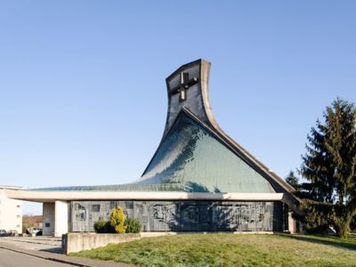 Eglise Saint-Jean, Dole (Jura), janv 2017 caue 39 : vue d'ensemble - arc en béton terminé par un clocher-mur, toiture formée de deux paraloboïdes hyperboliques, couverture en cuivre, mur-rideau sous forme de grille-sculpture - DOLE (39100)