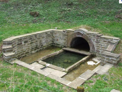 La Charme, 2017 F. Leng photo / CAUE39 : Lavoir avec un bassin rectangulaire en pierre, situé en contrebas du sol environnant. Le lavoir est alimenté par le captage d'une source, protégé par un tunnel en pierres et comportant une façade en demi-arc de cercle. - LA CHARME (39230)