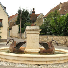 Thervay, F. Leng / CAUE39 : Fontaine avec un décor de trois cygnes imposants dans le bassin circulaire, provenant des forges de Baudin. La colonne centrale de section circulaire, en pierre, est surmontée d’un grand vase en fonte. Cette fontaine est l'œuvre de l'architecte BESAND qui construisit aussi la maison commune du village en 1836 - THERVAY (39290)